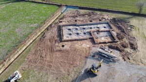Aerial view of site preparation and foundation work for a residential home under construction.