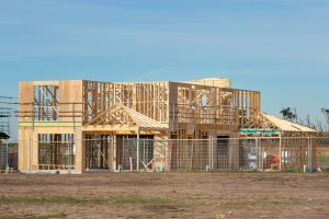 Stages of building a custom home showing a residential house under construction with wood framing.